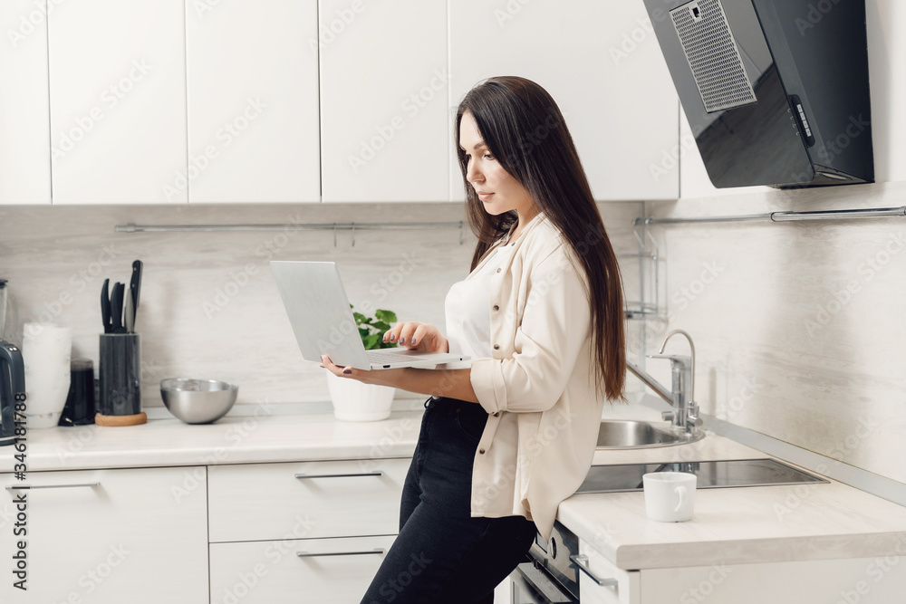 Young woman freelancer working online behind laptop in kitchen home. isolation worker concept Young woman freelancer working online behind laptop in kitchen home. isolation worker concept