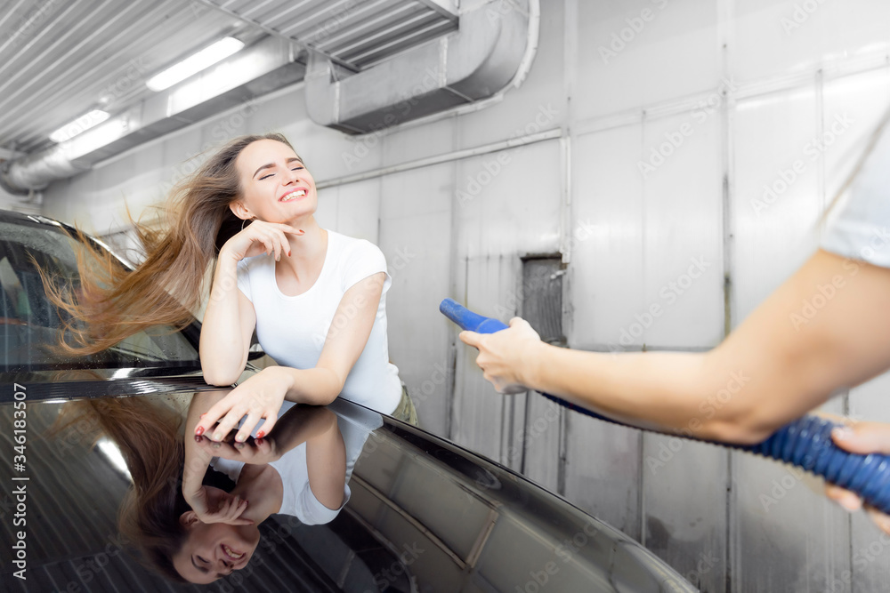 Girl worker uses turbo dryer to remove drops of water. Service car wash express Girl worker uses turbo dryer to remove drops of water. Service car wash express