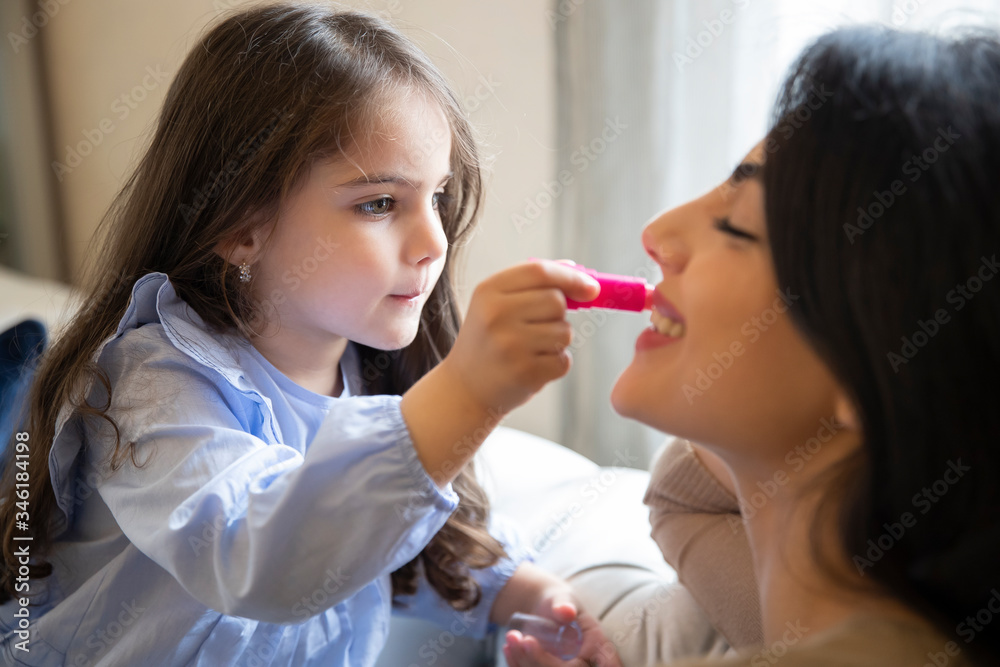 Happy loving family. Mother and daughter are doing make up and having fun at home. Close up portrait of daughter making up on her mom's face..