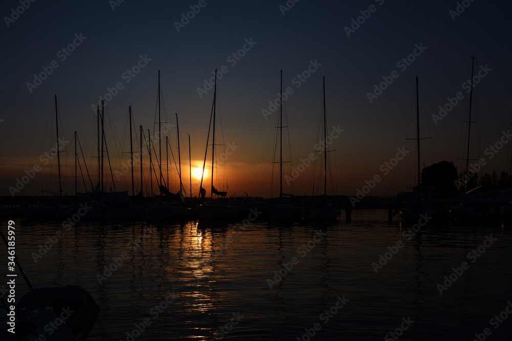 Yacht Parking at sunset with the reflection of masts in the water.