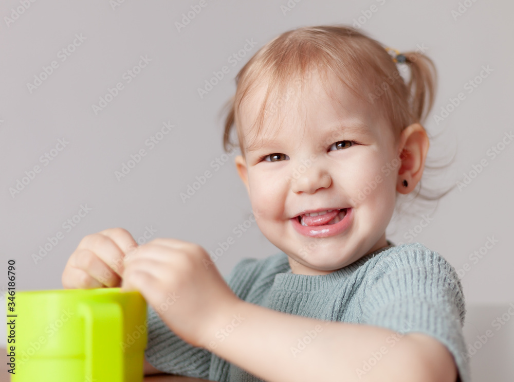 Happy little girl sits at a table and smile, with copyspace on left side, isolated over white Happy little girl sits at a table and smile, with copyspace on left side, isolated over white