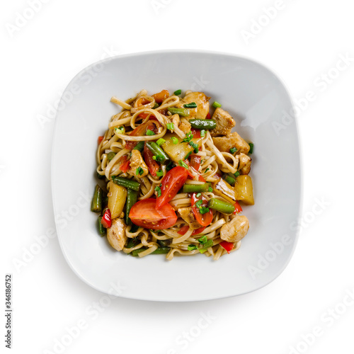 Fried udon noodles in a wok with chicken, string beans and pineapple slices. Traditional asian food. Isolated on a white background.