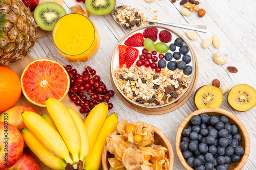 Group Fruits Breakfast mixed vegetables with salad bowl, nuts bowl, strawberry, banana, and pineapple, orange juice, vitamin c in food nature for health and diet in the top view on the wood table.