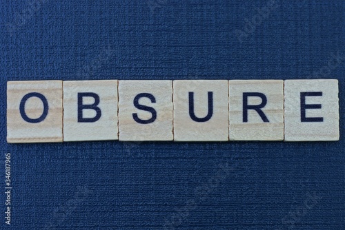 text the word obsure from gray wooden letters on a black table photo