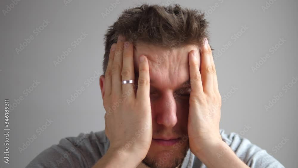 Upset Unhappy Stressed Young Man Squeezing Head With Hands, Suffering From Headache. People, Stress, Tension And Migraine Concept. Upset Unhappy Stressed Young Man Squeezing Head With Hands, Suffering From Headache. People, Stress, Tension And Migraine Concept.