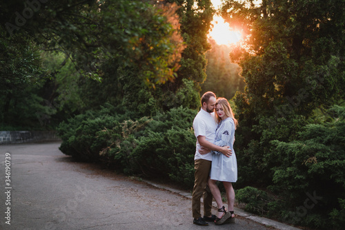 Romantic and happy caucasian couple in casual clothes hugging on the background of beautiful nature. Love, relationships, romance, happiness concept. Man and woman walking outdoors together. © anna_gorbenko