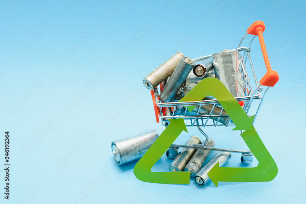 waste recycling, garbage disposal, environment and ecology concept - close up of used alkaline batteries and green recycling symbol