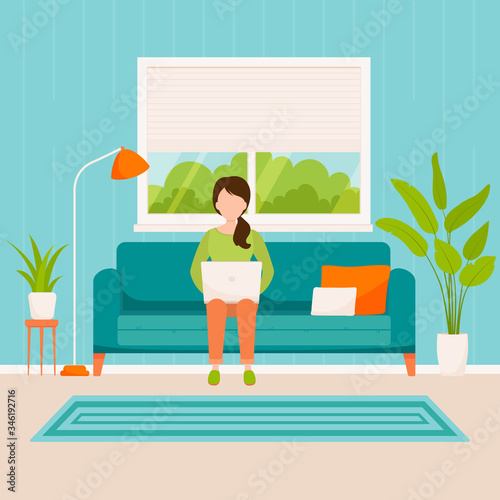 woman with a laptop working or studying at home sitting on a sofa in the living room.