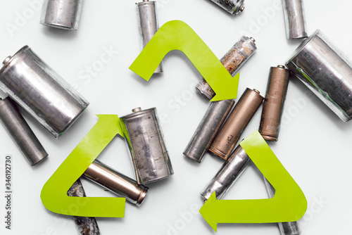 Use AA and properly dispose of batteries that are toxic to the environment and soil against a green background. The concept of technologies for processing hazardous and recyclable substances.