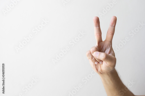 closeup hand indicating peace victory sign on white brick wall background