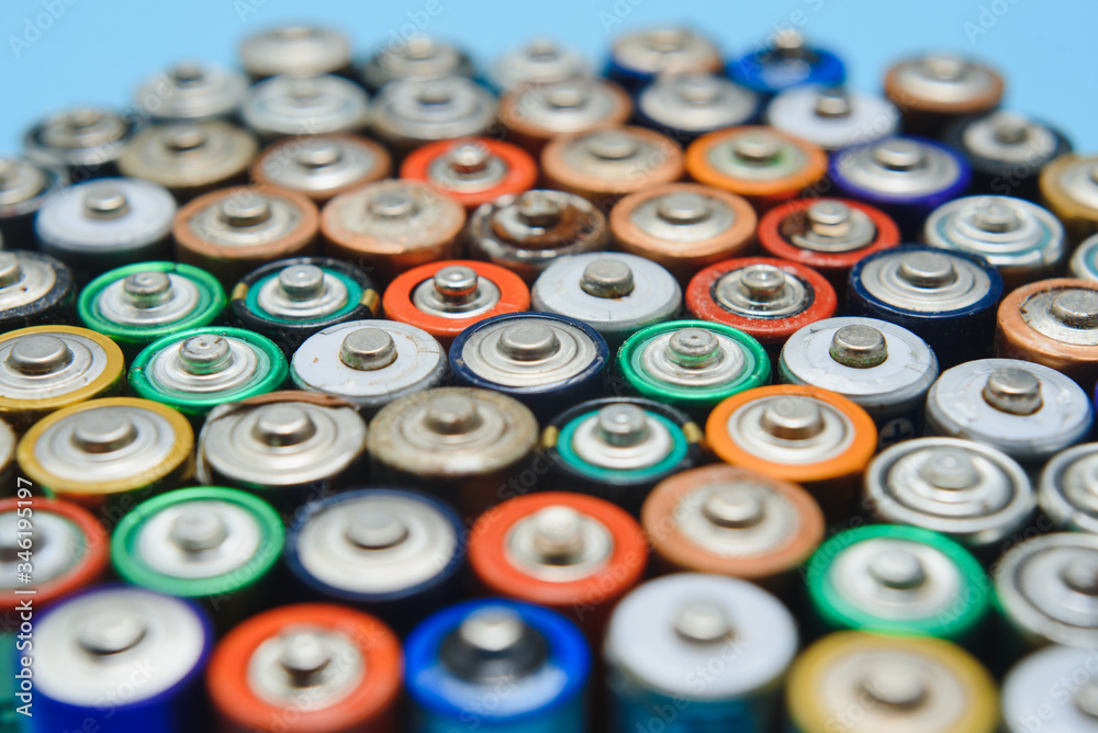 Close up of positive ends of colorful discharged batteries of different sizes and formats, top view, copy space. Used alkaline battery on concrete background. Hazardous garbage concept. Close up of positive ends of colorful discharged batteries of different sizes and formats, top view, copy space. Used alkaline battery on concrete background. Hazardous garbage concept.