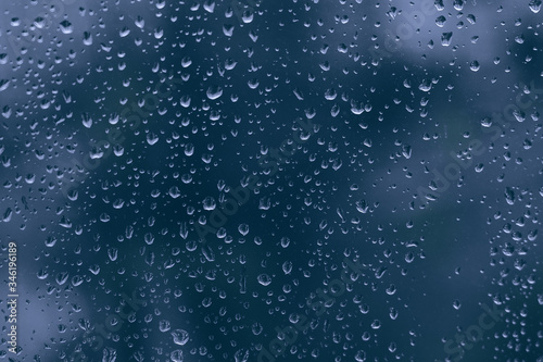 Close up of water rain droplet on a dark blue glass dripped window. big rainy drop on a window pane during a shower stormy weather. rainy season in the city.