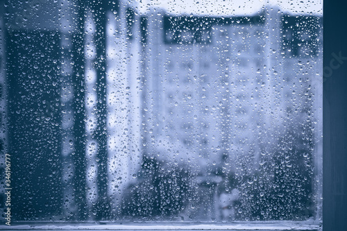 rainy droplets on a blue window glass transparent surface. drops on window shield in a rainy days in night city. stormy weather. isolation sad depression concept. rainy season. stay home.