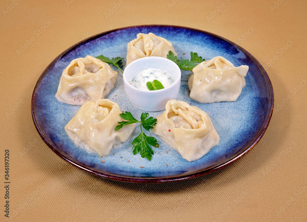 Uzbek manti on a blue plate with cream sauce
