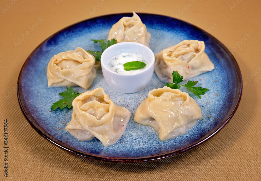Uzbek manti on a blue plate with cream sauce
