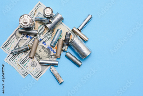 Old used batteries and banknote of one hundred dollars. Recycling concept. Save environment. Cost, purchase or sale of electricity
