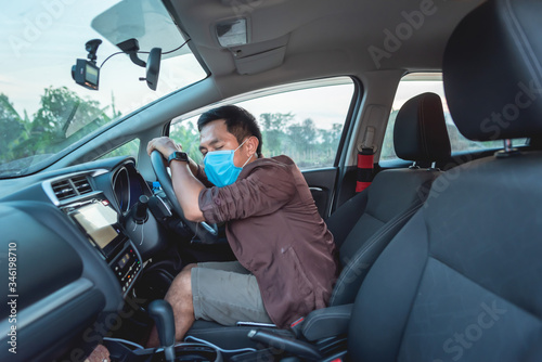 A man sat in a car and had a protective mask.