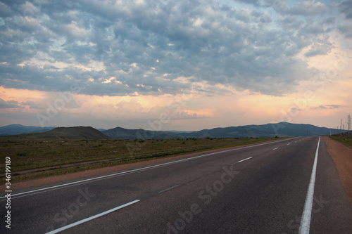 Beautiful landscape, sunset, sky in beautiful clouds and a road stretching into the distance