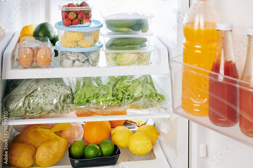 Full refrigerator after groceries delivery  citrus fruits  vegetables and greens on shelves