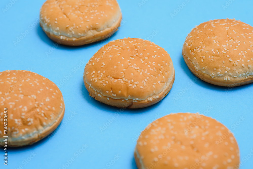 Burger bun empty isolated. American food classic round burger bread isolated on a blue background. Grilled burger bun top.Close-up.