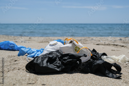 Ffp protective virus mask and plastic gloves garbage trash on sandy sea coast,coronavirus covid pollution disease 