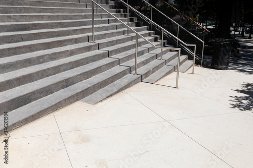 Fototapeta Naklejka Na Ścianę i Meble -  Wide gray concrete stairs in an outdoor urban street landscape, metal railing, creative copy space, horizontal aspect