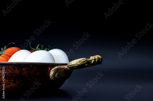 Traditional turkish food menemen materials; tomatoes and eggs in copper pan on background. Recipe  photo