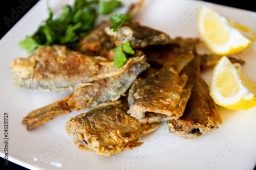 Fried fish on a white plate. Grilled crucian with lemon and parsley.