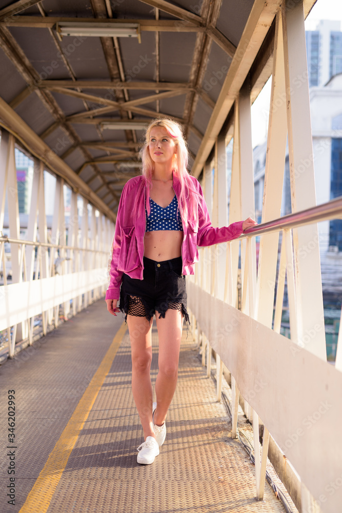 Young beautiful blonde woman at footbridge in the city