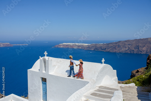A man and a woman holding hand on the background on Santorini Island. The village of Imerovigli..He is an ethnic gypsy. She is an Israeli.