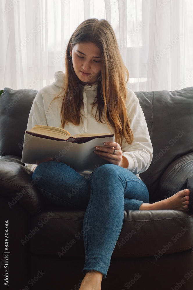 Reading and development. Beauty young woman is reading a book at home. Thoughtful girl reading important book Reading and development. Beauty young woman is reading a book at home. Thoughtful girl reading important book
