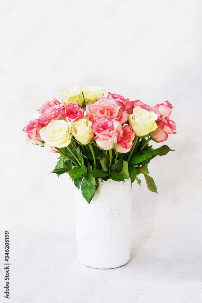 Bouquet of pink and white roses in white vase on light background. Copy space for text. Holiday background. Mother's day, Valentines Day, Birthday celebration concept. 