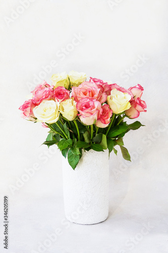 Fototapeta Naklejka Na Ścianę i Meble -  Bouquet of pink and white roses in white vase on light background. Copy space for text. Holiday background. Mother's day, Valentines Day, Birthday celebration concept. 