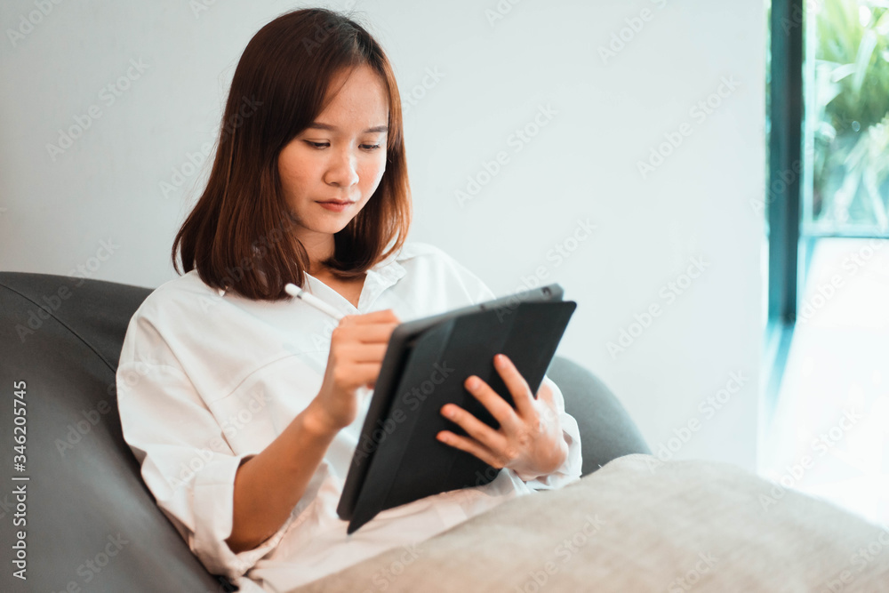 young woman working on tablet computer while sitting at the living room. work from home concept young woman working on tablet computer while sitting at the living room. work from home concept