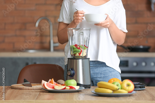 Young woman making smoothie...