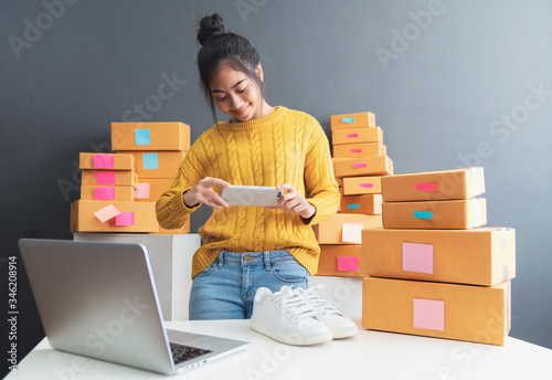 Foto Young women taking photo to shoes with cell telephone or smartphone digital camera for post to sell online on the Internet and preparing pack product box