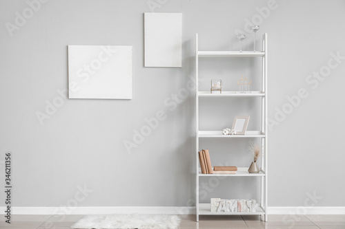 Rack with stylish decor near grey wall in room