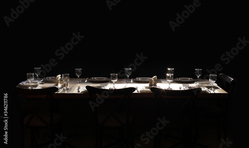Dining table served with plates, glasses, forks and knives. Without food. On a black background.