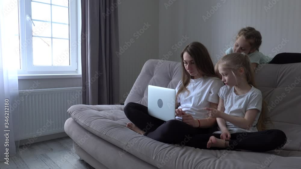 Family is using mobile devices together sitting on sofa during weekend at home. mother and two kids daughter holding smartphones Family is using mobile devices together sitting on sofa during weekend at home. mother and two kids daughter holding smartphones