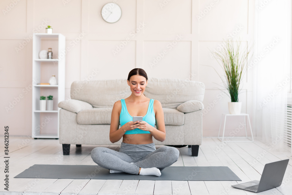 Fitness Girl Using Smartphone Watching Training Video On Laptop Indoors Fitness Girl Using Smartphone Watching Training Video On Laptop Indoors