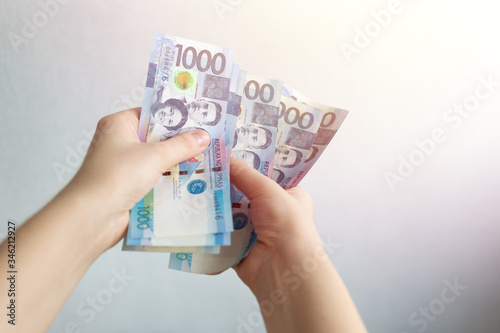Hands holding cash banknote of one thousand Philippines peso paying bills, payment or salary. White background, close up