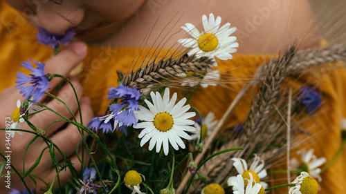 A girl in a yellow blouse with a bouquet of field flowers