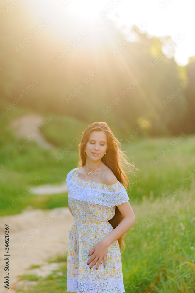 Portrait of a young beautiful girl in a sundress. Summer photo session in the park at sunset. Close-up shot. Portrait of a young beautiful girl in a sundress. Summer photo session in the park at sunset. Close-up shot.