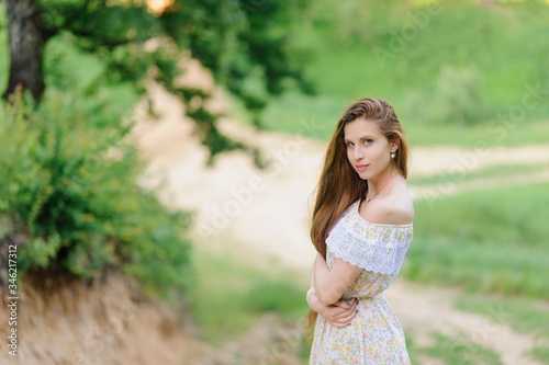 Portrait of a young beautiful girl in a sundress. Summer photo session in the park at sunset.