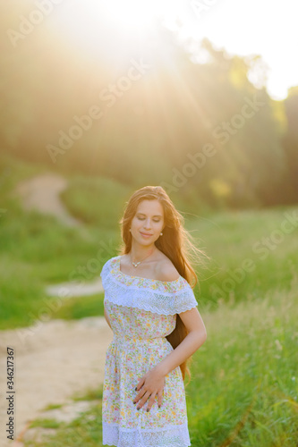 Portrait of a young beautiful girl in a sundress. Summer photo session in the park at sunset. Close-up shot.