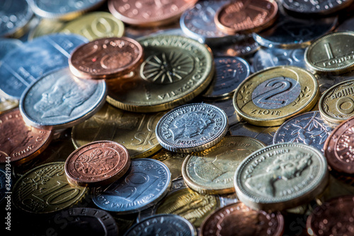 Old and new metal coins from around the world, illuminated in bright light in a studio, close-up detail.