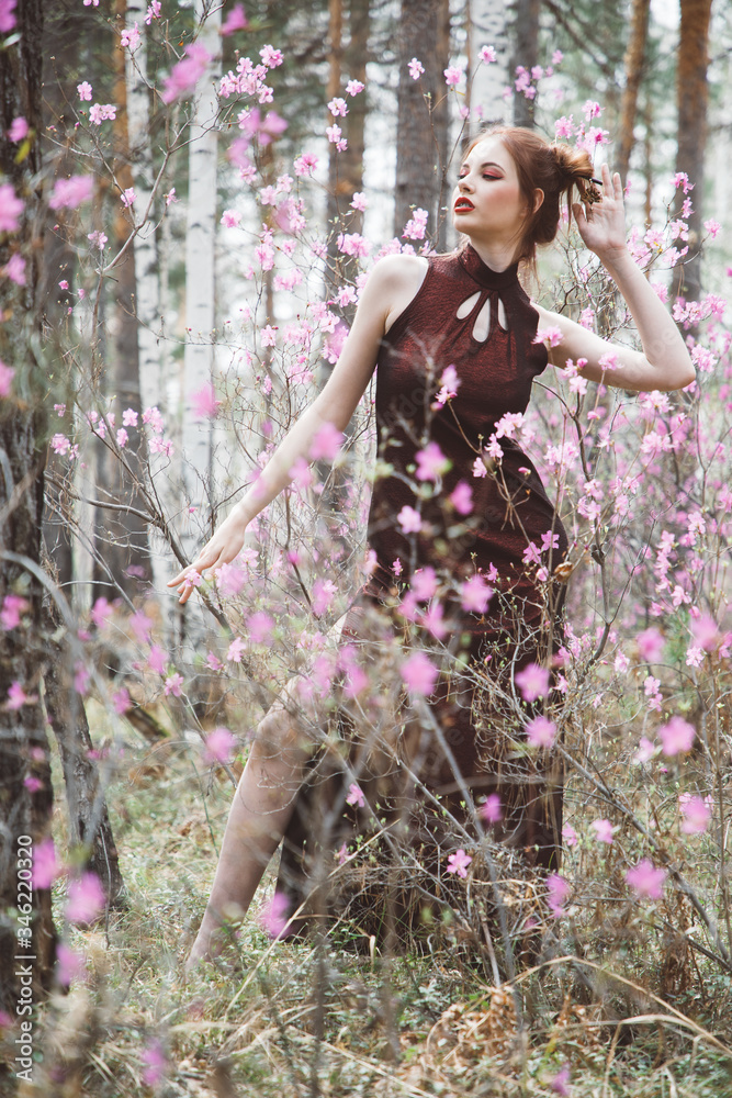 A girl dressed in Japanese style in a flowering forest among pink flowers A girl dressed in Japanese style in a flowering forest among pink flowers