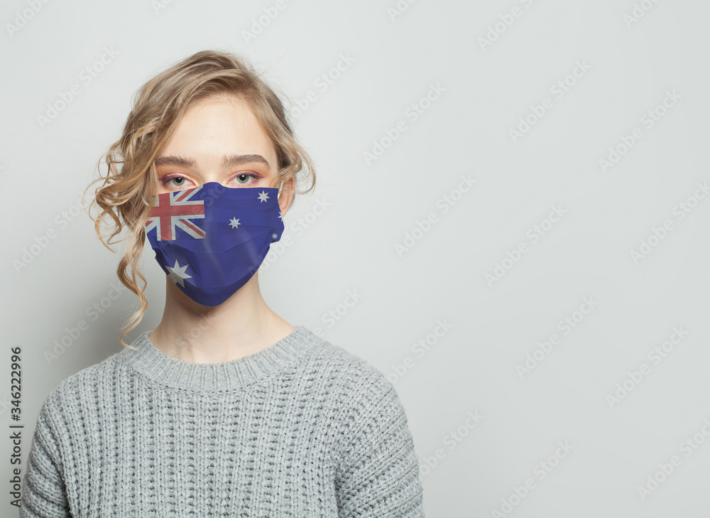 Young woman wearing a protective mask with national flag australia. Flu epidemic and virus protection concept Young woman wearing a protective mask with national flag australia. Flu epidemic and virus protection concept