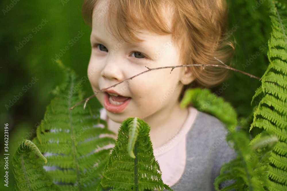 little emotional girl smiling playing in beautiful green thickets of fern, hiding behind large leaves. girl playing hide and seek in beautiful thickets. happy childhood little emotional girl smiling playing in beautiful green thickets of fern, hiding behind large leaves. girl playing hide and seek in beautiful thickets. happy childhood