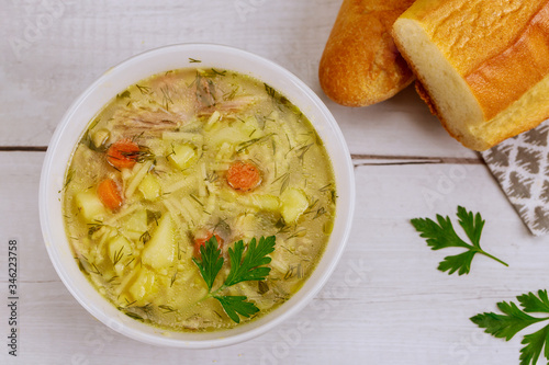 Plate full of chicken noodle soup with bread.